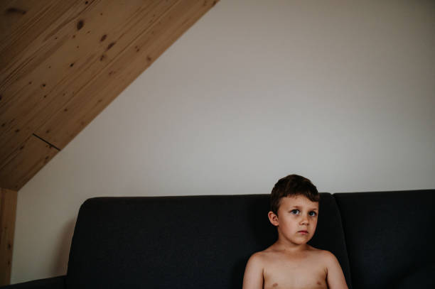 istock Portrait of sad little boy sitting on sofa alone. 1406541825