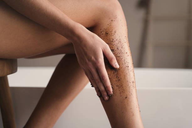 gros plan d’une femme se frottant les jambes dans la salle de bain pendant le massage anti-cellulite avec gommage au café - exfoliation photos et images de collection