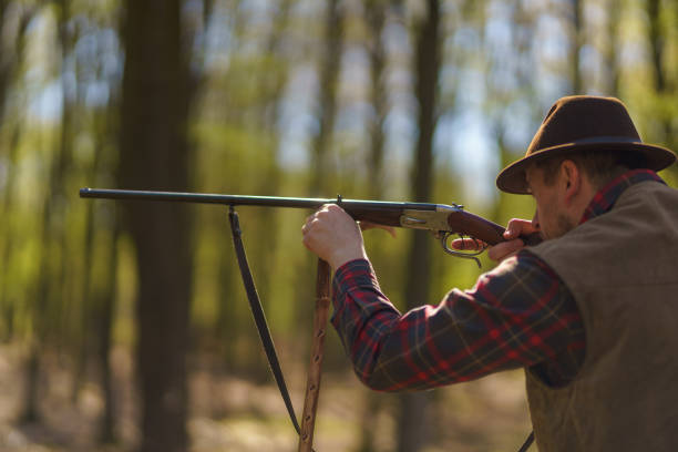 istock Hunter man aiming with rifle gun on prey in forest. 1406543308