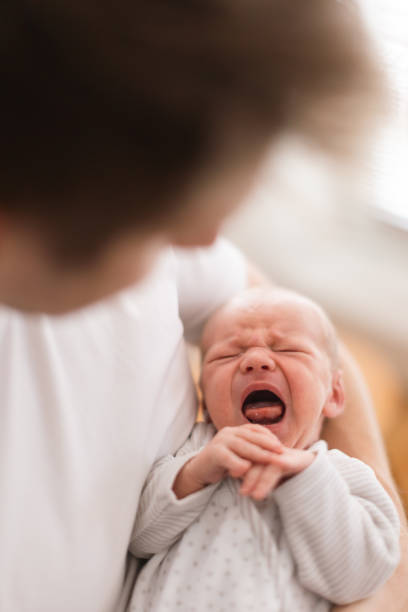 istock Father holding his crying newborn son at home. 1406546909