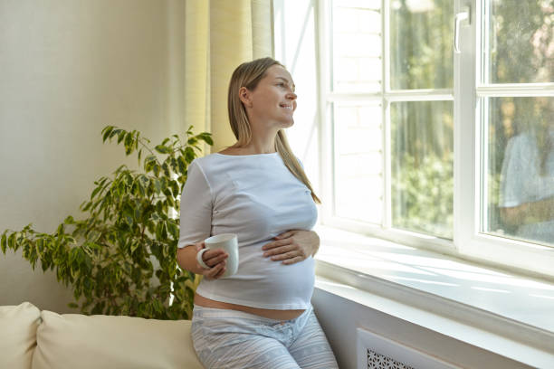 istock Woman in standing by the window and drinking coffee 1406547072