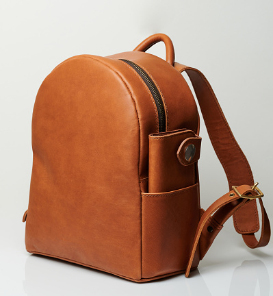 Brown backpack with wallet in pocket isolated on studio background