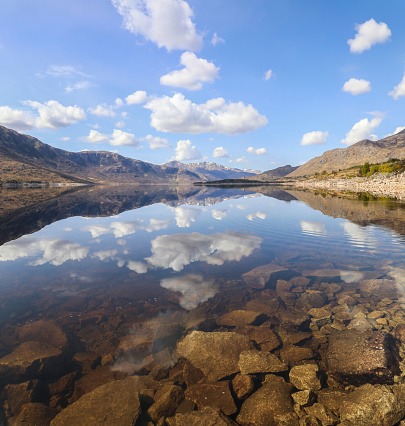 Panoramic view of a perfect lake reflection of clouds and mountains in Dundreggan Reservoir in Northern Scotland