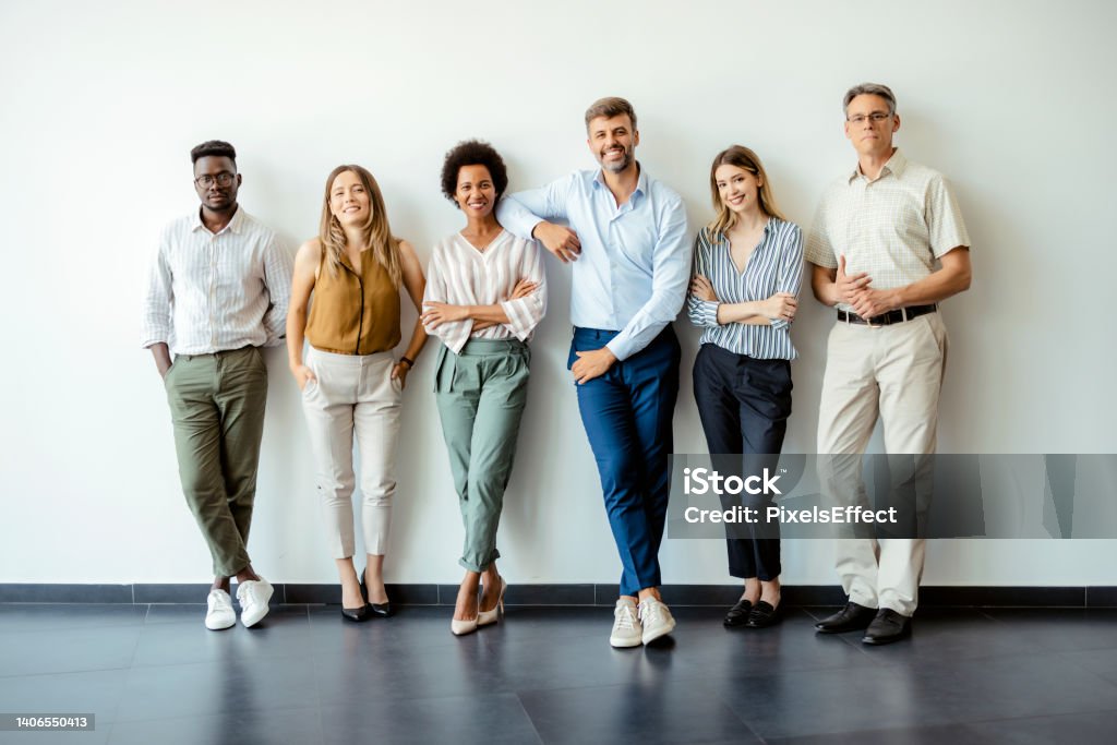 Success is simply what we're good at Group portrait of happy business people in smart casual outfits posing against office wall background. Smiling and looking at camera Employee Stock Photo