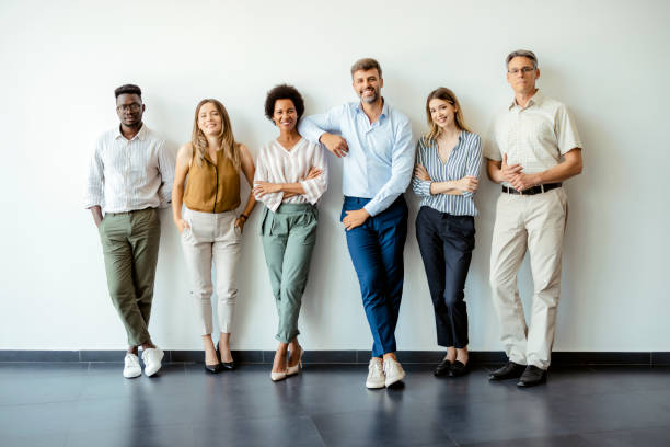 Success is simply what we're good at Group portrait of happy business people in smart casual outfits posing against office wall background. Smiling and looking at camera man and woman differences stock pictures, royalty-free photos & images
