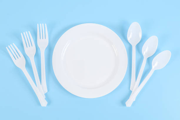 istock Empty plastic plate with forks and spoons on the sides on a blue. 1406550504