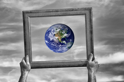 Man holding a frame and showing planet.