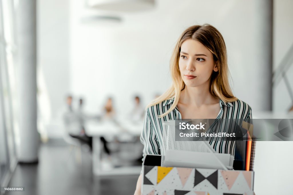 Upset businesswoman being fired Upset businesswoman with cardboard box of things leaving office after being fired Quitting a Job Stock Photo