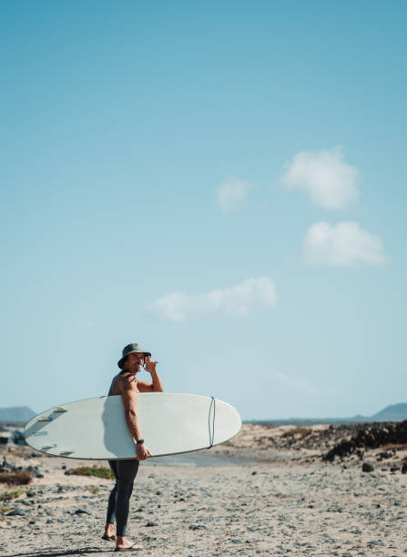 istock Man walking on the beach with surfboard to go surfing 1406551903