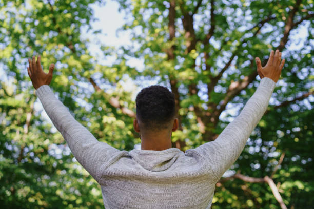 istock Rear view of happy young man doing stretching exercise and raising hands up outdoors in forest, weekend away and digital detox concept. 1406553636