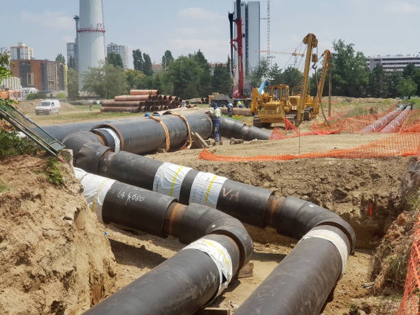 istock Laying heating pipes in a trench at construction site. 1406554484