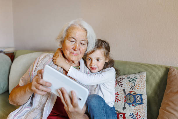 istock Grandmother and granddaughter on the sofa using a tablet together 1406554699
