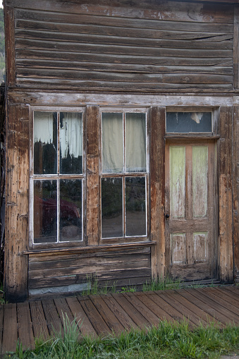 Rusty vintage car and idyllic wooden houses decay in the American wilderness after the gold rush. Scenic view of a ghost town in the Californian countryside slowly falling apart in rugged conditions.