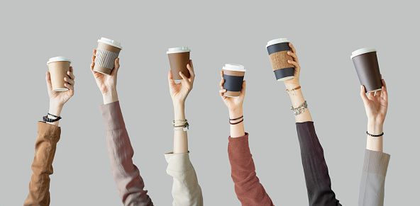 Many different arms raised up holding coffee cup