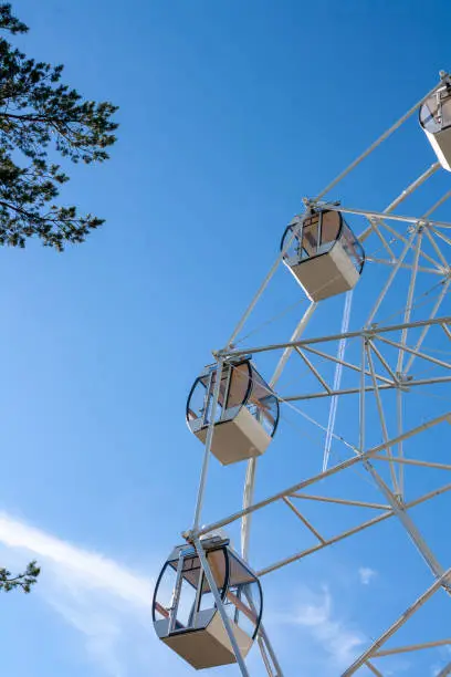 Photo of fragment of a Ferris wheel on a background of blue sky and clouds