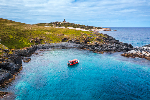 Aerial view of a boat moored at Montague Island, a nature reserve off the south coast of Australia surrounded by clear blue water
