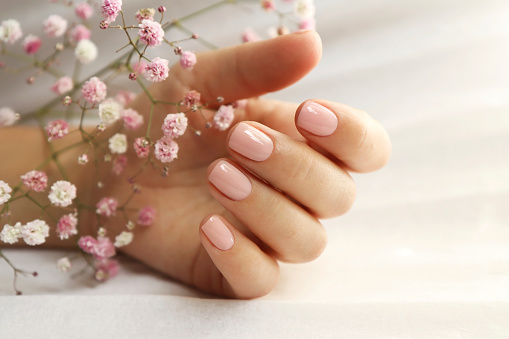 Light pink manicure on short nails .