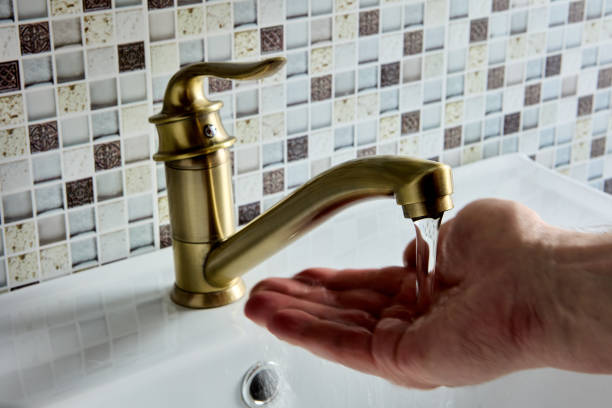miscelatore mono a gomito singolo in ottone in bagno, la mano sta controllando la temperatura dell'acqua. - bathroom water pipe faucet sink foto e immagini stock