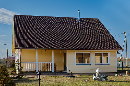 Country house with porch and veranda, covered siding, heated with wood.