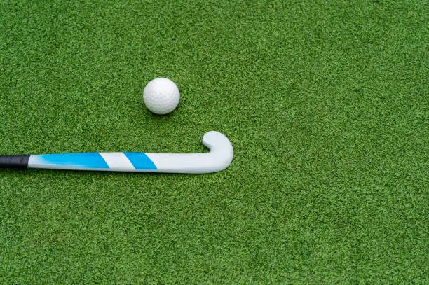 Field hockey stick and ball on green grass. Horizontal sport theme poster, greeting cards, headers, website and app
