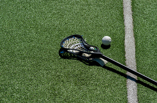 Lacrosse stick and white ball on green grass. Horizontal sport theme poster, greeting cards, headers, website and app