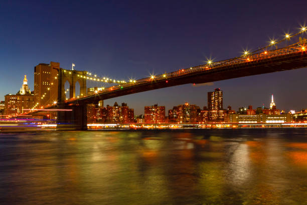 view of manhattan at dusk with the brooklyn bridge in the foreground - connection usa brooklyn bridge business imagens e fotografias de stock