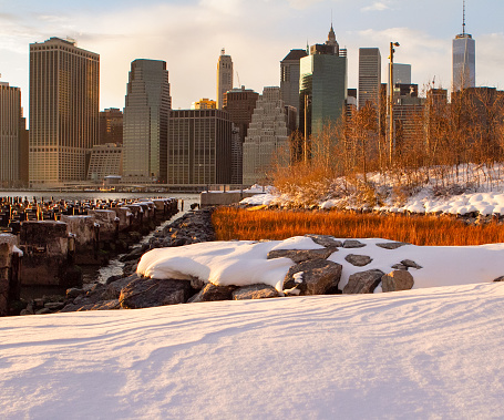 Lower Manhattan at sunrise with wooden piers in the foreground as well as snow