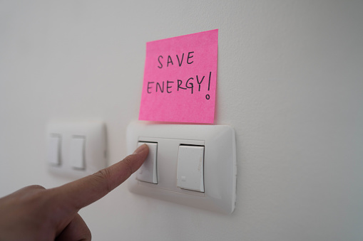 Employee turn off a light switch for save energy in sustainable office.