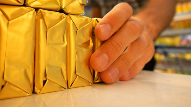 close-up of butter packagings on a supermarket fridge shelf and a male buyer's hand takes one - margarine dairy product butter close up imagens e fotografias de stock