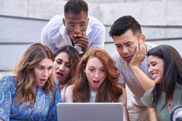 istock Group of multi-ethnic people look at laptop screen with a shocked expression on their faces. 1406574060