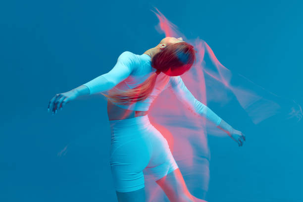 흰색 트랙수트에 스포티 한 아름다운 소녀가 파란색 배경에 춤을 추고 있습니다. 모션 블러 효과가있는 스튜디오의 고립 된 피트니스 모델. - sport white women fashion model 뉴스 사진 이미지