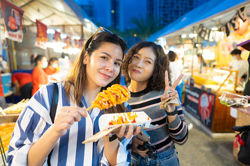 Asian friends tourist enjoy outdoor lifestyle eating street food together.