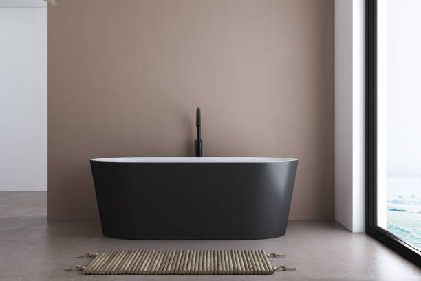 istock A black-white bathtub standing on a concrete floor with beige wall background. 1406581151