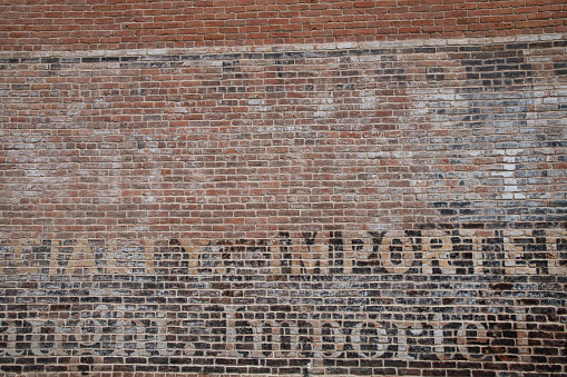 Brick wall with nondescript faded letters in old west town in central Colorado, USA.