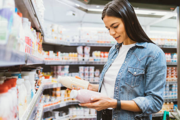 retrato de mujer joven en el supermercado sosteniendo dos botellas - milk bottle fotos fotografías e imágenes de stock