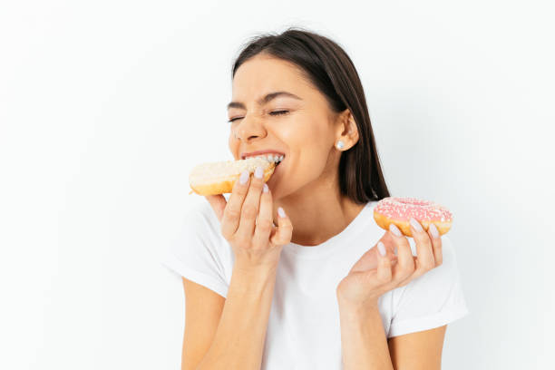 istock Happy young woman eating doughnuts 1406590736