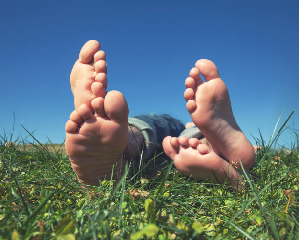 primer plano de dos pies de personas y sus dedos de los pies acostados en hierba tonificada con un filtro retro vintage de instagram - barefoot behavior toned image close up fotografías e imágenes de stock