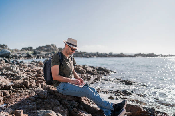 istock digital nomad sitting on the shore of the beach alone working relaxed 1406595875