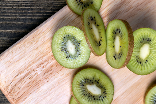 sliced green ripe kiwi, sliced green kiwi fruit on a wooden board