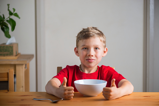 Cute boy eats granola for breakfast. Lifestyle portrait. Natural light. Genuine expressions.