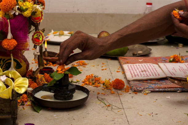 un prêtre hindou offrant des fleurs à shiva linga à l’occasion de la première fois qu’un individu entre dans sa nouvelle maison. graha pravesh entre dans la nouvelle maison. - soi bangla photos et images de collection