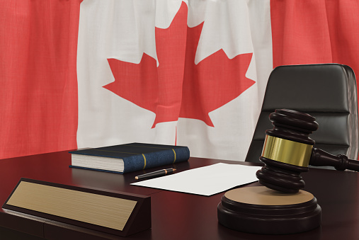 Law and justice concept,  gavel on a wooden desktop and the Canada flag on background. 3d render.