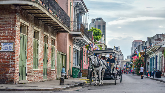 New Orleans, LA, USA - June 30, 2022: Tourists enjoying a horse-drawn carriage ride on Bourbon Street in the heart of the French Quarter of New Orleans, Louisiana.