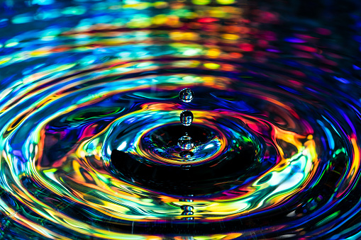 A macro low angle close up of a water drop in colorful water.