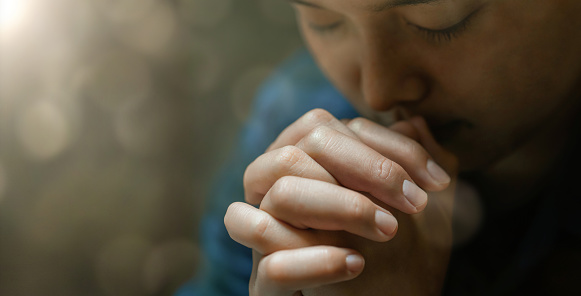 Una joven se sienta en oración por una oración de crisis de vida cristiana a Dios. Ideas de oración para las bendiciones de Dios para una vida mejor manos femeninas orando a Dios fe en el bien photo
