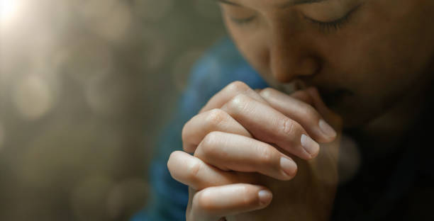 una giovane donna siede in preghiera per una preghiera di crisi della vita cristiana a dio. idee di preghiera per le benedizioni di dio per una vita migliore mani femminili che pregano dio fede nel bene - please god foto e immagini stock