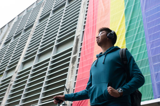 un joven orgulloso mira al horizonte en el fondo de la bandera lgbt - gay pride flag audio fotografías e imágenes de stock