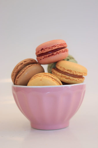 Macarons in different colors and flavors in a pink bowl