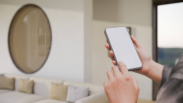 istock A female hands holding a smartphone mockup over blurred modern comfortable living room 1406624889