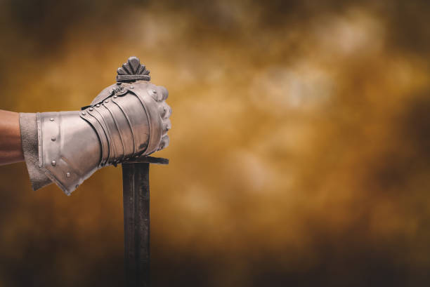 Sword. Knight hand with the sword close up on the orange background. Sword stock pictures, royalty-free photos & images